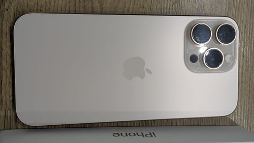 Retro dell'iPhone 16 Pro Max usato color Desert Titanium con le tre fotocamere, sopra la scatola originale